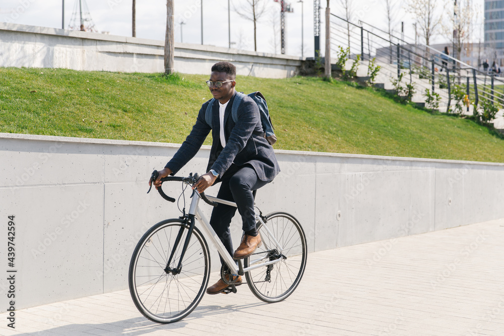 Young african american businessman riding a bicycle to work in the urban city zone Young african american businessman riding a bicycle to work in the urban city zone