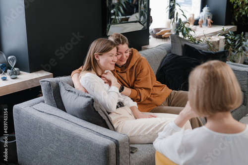 Delighted couple of women cuddling during psychotherapy consultation photo