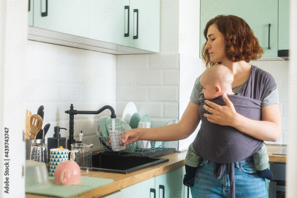 Woman With A Baby Pouring A Glass Of Water Woman With A Baby Pouring A Glass Of Water