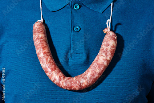 man wears a raw sausage as a necklace photo