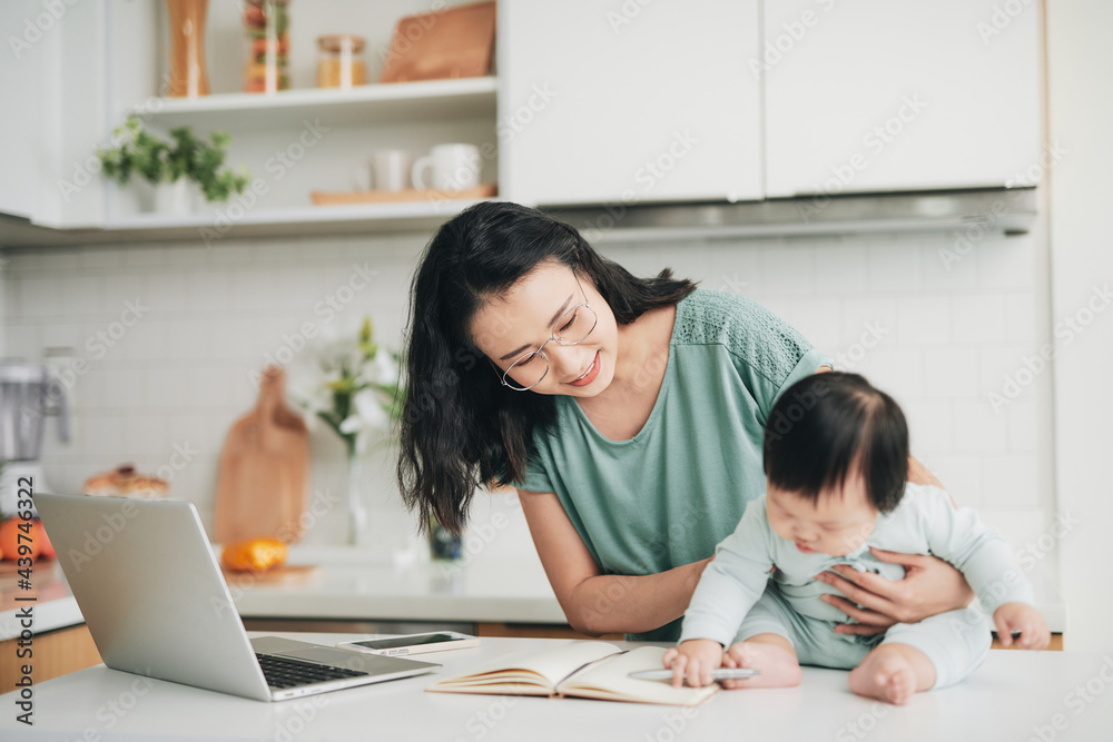 Happy young mother with baby using laptop at table in morning Happy young mother with baby using laptop at table in morning