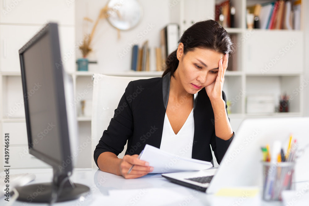 Fototapeta premium Tired businesswoman working with documents in business office