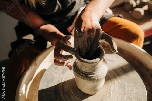 Hands, clay and pottery wheel shot in the harsh light photo