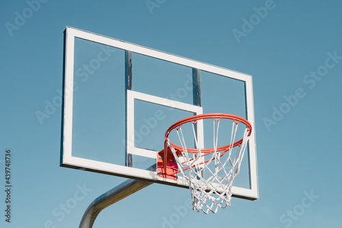 Glass basketball backboard against blue sky photo