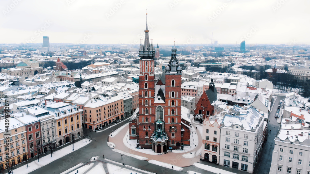 Fototapeta Aerial view of the Krakow’s Rynek Głowny (Central Square) surrounded by historic buildings. Twin towers of the Basilica of Saint Mary against clear white sky in the background. City Skyline.