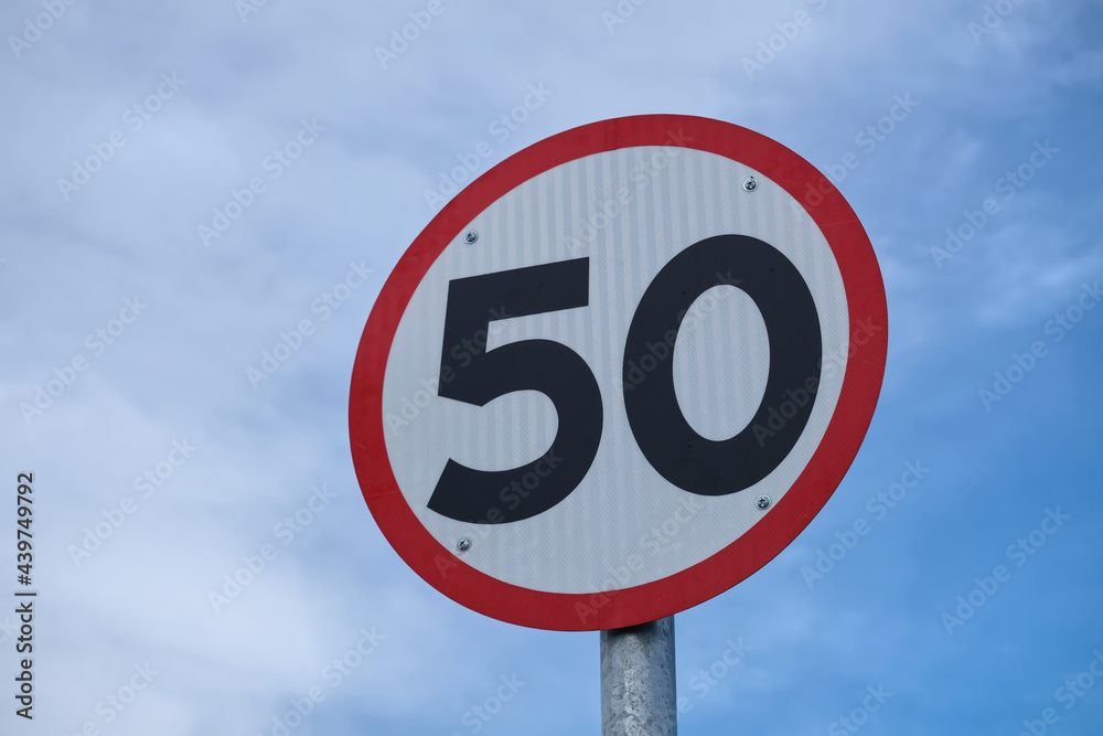 Speed limit 50 sign on road, blue sky with clouds background