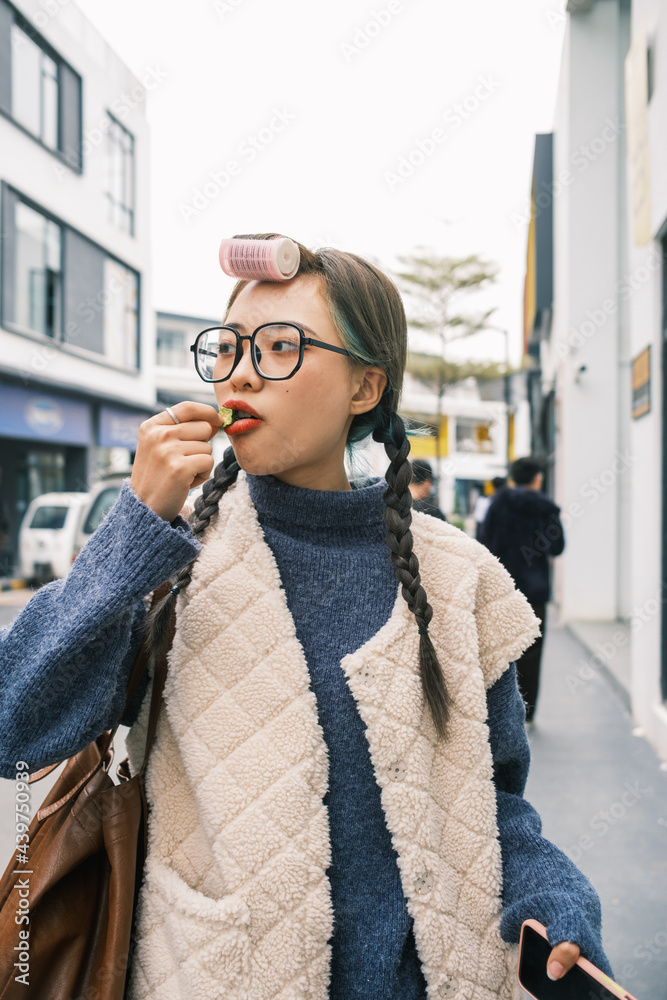 © Pansfun Images/Stocksy - Young Asian woman eating snacks