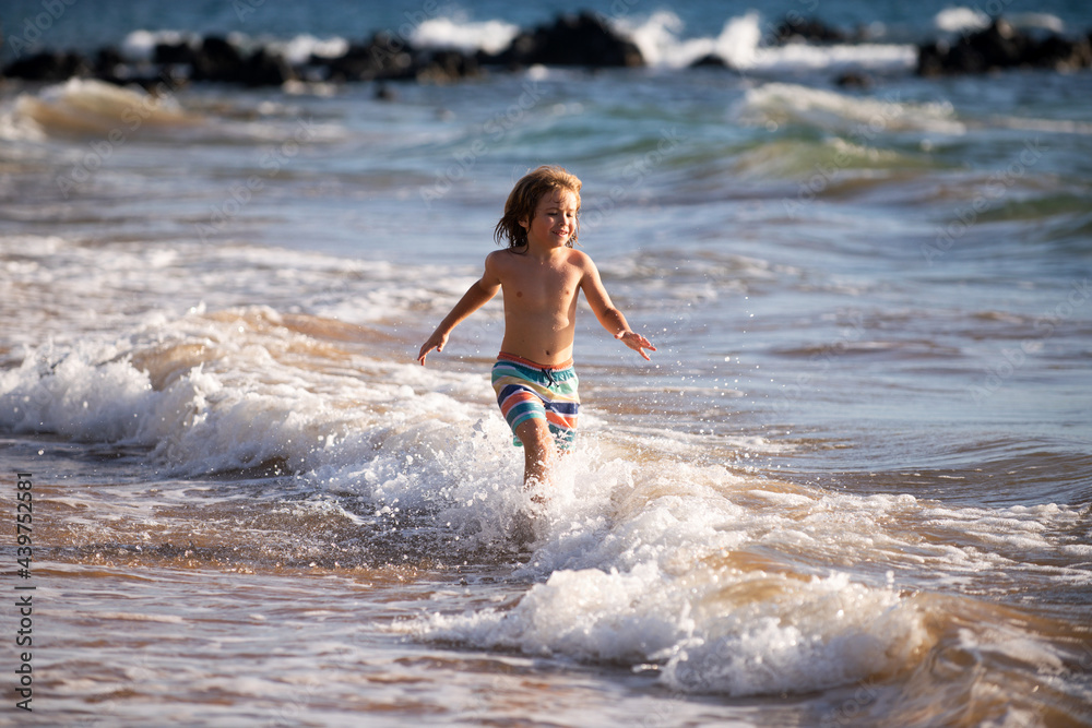 Fototapeta premium Boy kid jumping in sea waves. Jump by water sea splashes. Summer kids vacation.