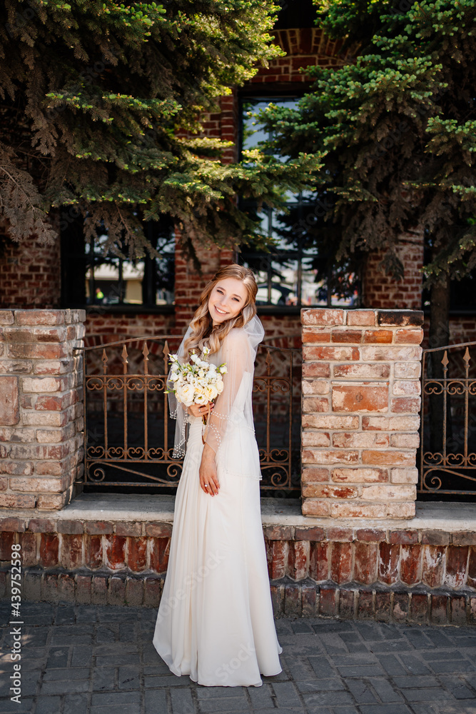 full-length. happy and beautiful bride with a bouquet of flowers at the fence.