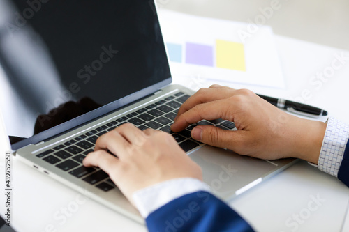 Laptop on office tablen with business man's hand in navy blue suit typing . Concept for cool style workplace photo