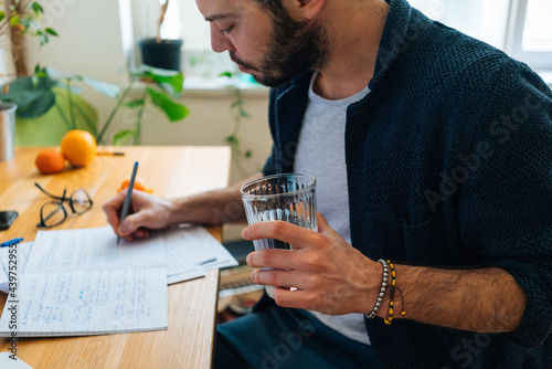 Handsome young adult man writing at home office