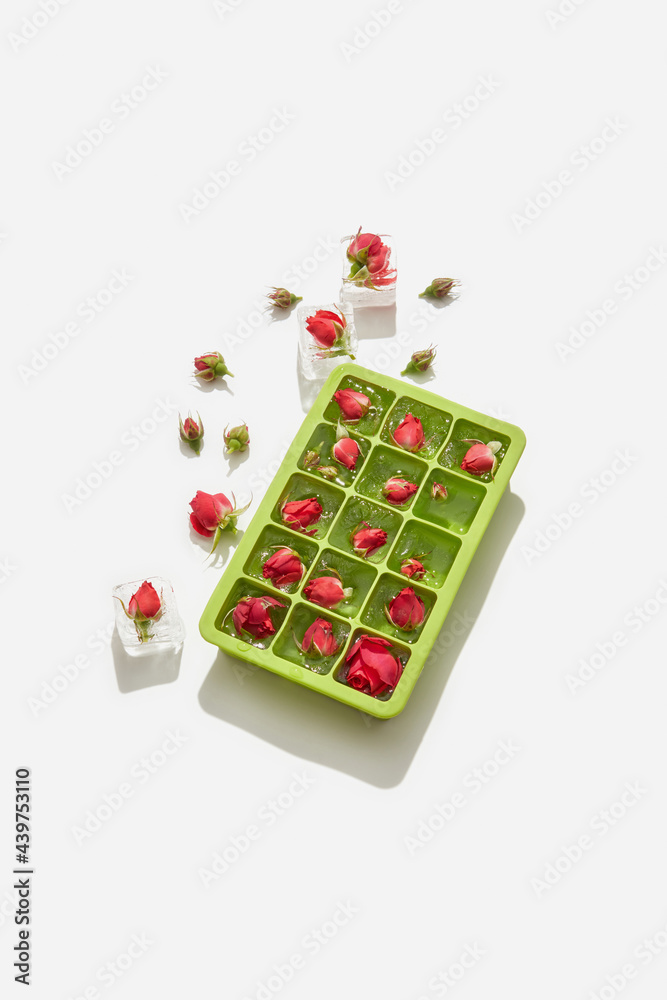 Ice cubes with roses in green ice box Ice cubes with roses in green ice box
