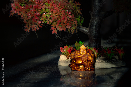 Laughing Buddha Statue on under the Tree. Statue of Laughing Buddha. Statue of kubera. photo