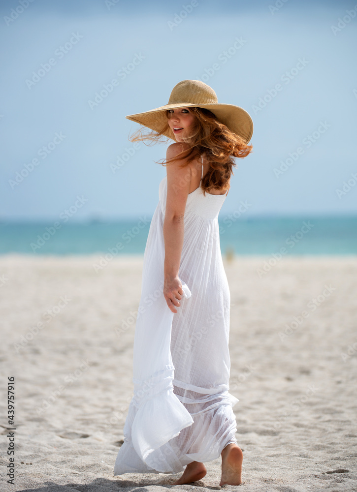 Summer model posing on the beach. Summer dress fashionable woman clothes. Young beautiful hipster woman with straw hat and summer dress, summer trend style.