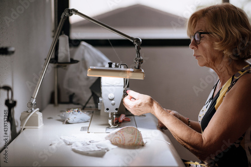 Adult tailor sewing masks, handmade work photo