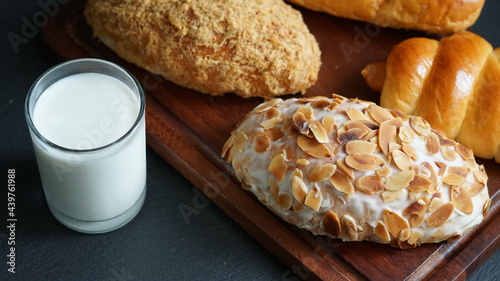 A glass of milk and various kinds of pastries on wooden board