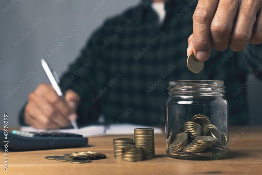 Putting a coin in glass jar with stack coins and whiting account saving money investment an idea concept.