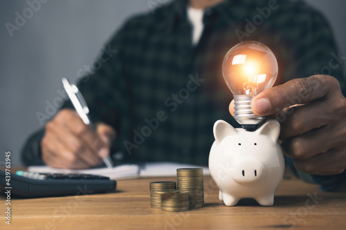 Holding light bulb piggy bank with stack coins and whiting account saving money investment an idea concept.