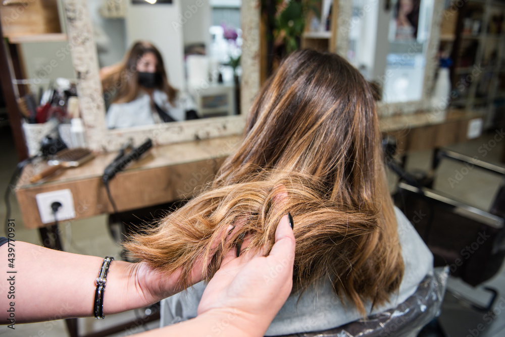 hairdresser doing curls to a client, brown hair with blonde highlights in the hair salon. beauty salon hairdresser doing curls to a client, brown hair with blonde highlights in the hair salon. beauty salon