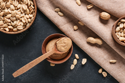 Tasty peanut butter with nuts on dark background