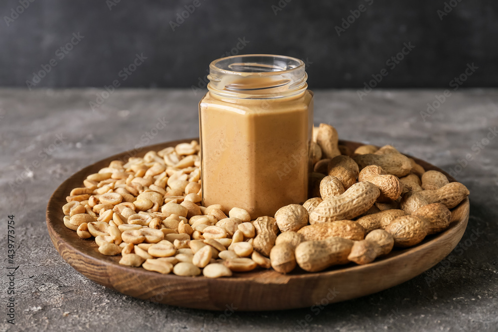 Jar with tasty peanut butter and nuts on grunge background Jar with tasty peanut butter and nuts on grunge background
