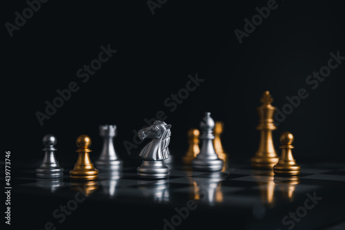 Gold king winner surrounded with silver chess pieces on chess board game competition.concept strategy, leadership and success business.