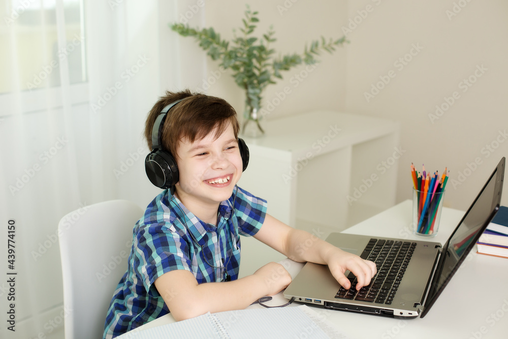 boy with headphones is laughing, studying at the computer at home boy with headphones is laughing, studying at the computer at home