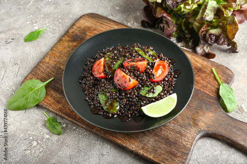 Plate with tasty cooked lentils and vegetables on grunge background