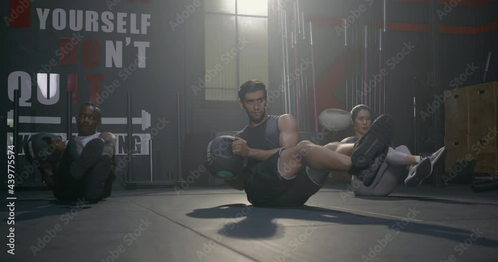 Young muscular athletic group doing training abdomen exercises working out with a medicine ball in fitness gym, strength workout healthy lifestyle sport concept