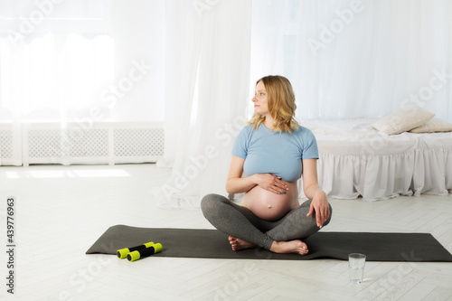 blonde pregnant woman doing yoga in the bedroom, Morning exercises