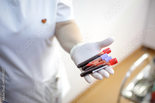 Shallow depth of field  selective focus  details with a female medical worker holding blood vials after a blood donation.
