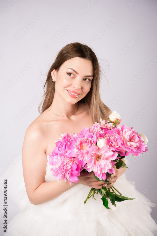 Beautiful smiling woman with a wreath of peonies on the head