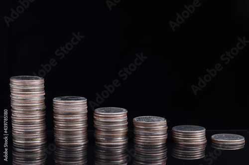 Tela Stacks of coins worth going down on black background
