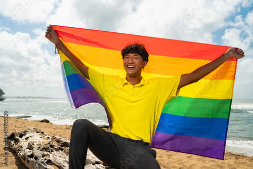 Young gay man proudly holding the lgbt flag in his hands