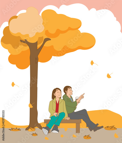 ベンチでイチョウの落ち葉を楽しむカップル