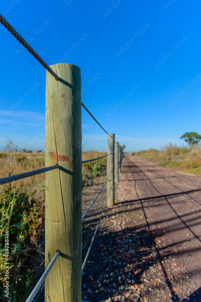 Fototapeta premium Cable fence running along gravel road