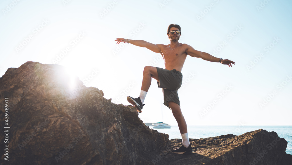 Giovane modello fa stretching muscolare su uno scoglio in riva al mare Giovane modello fa stretching muscolare su uno scoglio in riva al mare