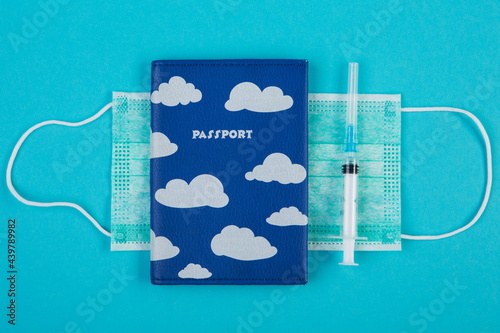 foreign passport and syringe lie on a medical mask, the concept of vaccination and prerequisites while traveling photo