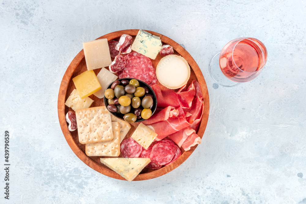 Charcuterie and cheese board, shot from above with a glass of rose wine. Prosciutto di Parma ham, blue cheese, olives and crackers, gourmet antipasti Charcuterie and cheese board, shot from above with a glass of rose wine. Prosciutto di Parma ham, blue cheese, olives and crackers, gourmet antipasti