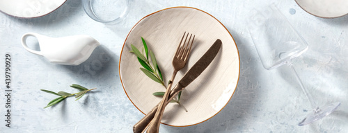 Modern tableware panorama, shot from above with olive branches. Mediterranean cuisine restaurant concept. Trendy plates, cutlery and glasses, top view