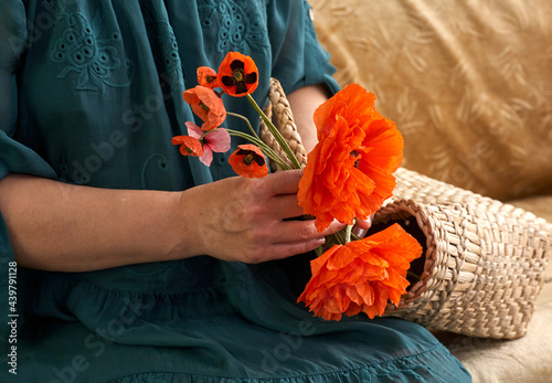 Woman in green dress holding poppe flowers, close up on her hands. Spring time dreams. © Igor Syrbu