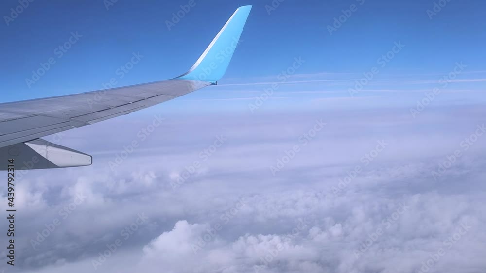 View of the wing of a flying plane high in the sky through the clouds in sunny weather. View of the wing of a flying plane high in the sky through the clouds in sunny weather.