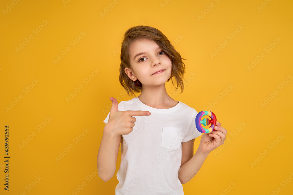 little girl holding pop it antistress toy on yellow background little girl holding pop it antistress toy on yellow background