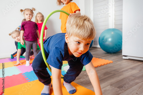 Photos Curly girl crawling on colorful floor through hula hoops