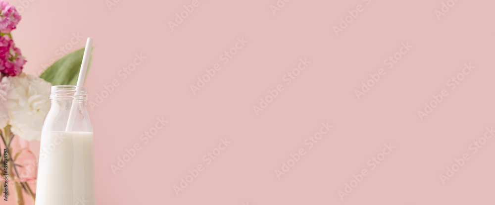 A bottle of milk on pink background with pink and white flower bouquet, bright and pastel drink composition A bottle of milk on pink background with pink and white flower bouquet, bright and pastel drink composition