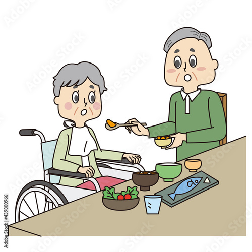 車椅子のシニア女性と食事介助するシニア男性