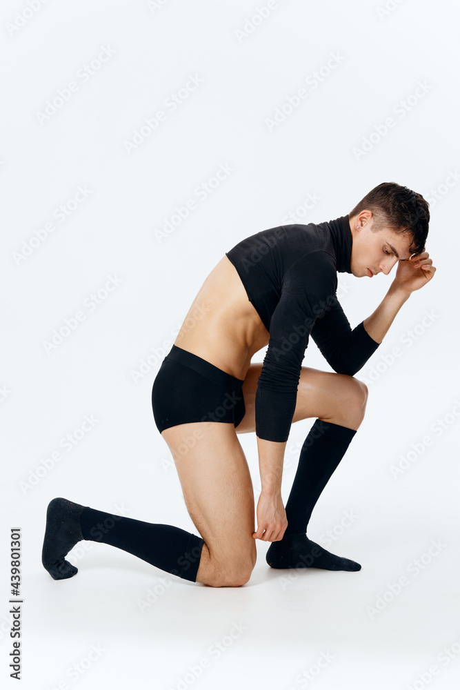 a man in a sweater and socks and underpants kneels in full growth on a light background a man in a sweater and socks and underpants kneels in full growth on a light background