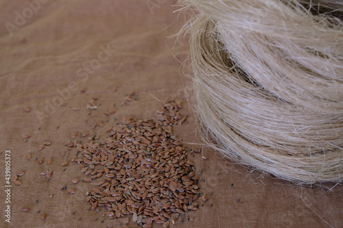 Flax seeds and flax tow on the brown flax canvas background. Copy space. 