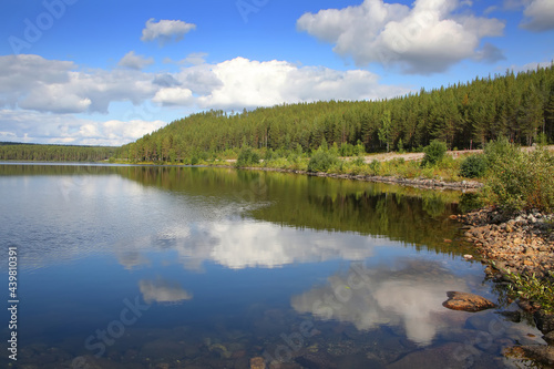 Beautiful landscape with a calm clear lake which has reflections of the trees and clouds. The lake lies within the Arctic circle near Polcirkeln  Northern Sweden  Scandinavia.