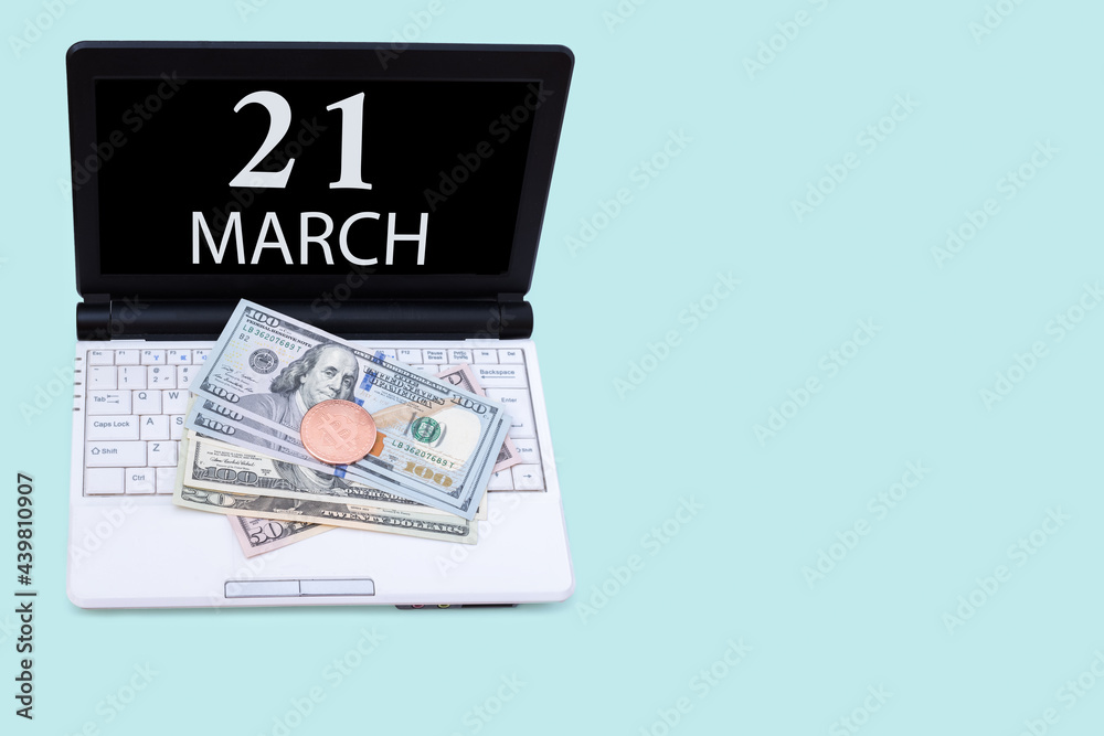Laptop with the date of 21 march and cryptocurrency Bitcoin, dollars on a blue background. Buy or sell cryptocurrency. Stock market concept. Laptop with the date of 21 march and cryptocurrency Bitcoin, dollars on a blue background. Buy or sell cryptocurrency. Stock market concept.